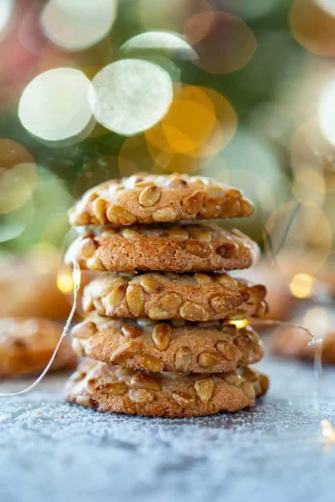 stack of 5 Pignoli Cookies in front of Christmas tree