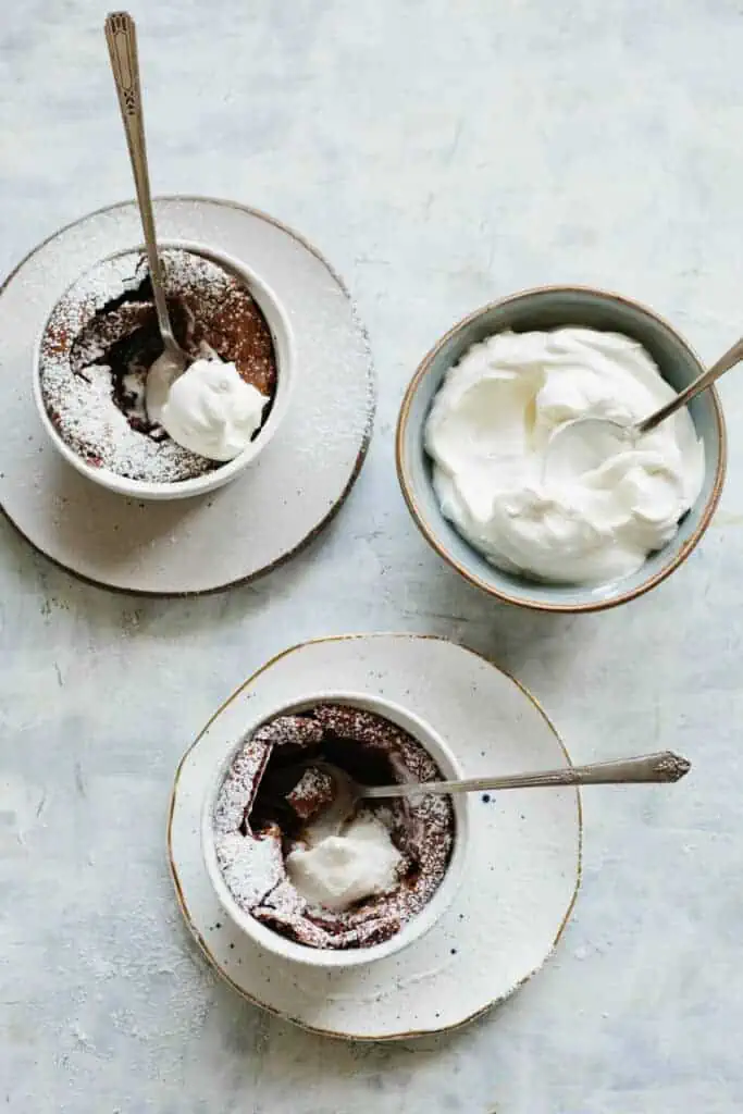 Two flourless chocolate souffles that have been garnished with whipped cream.