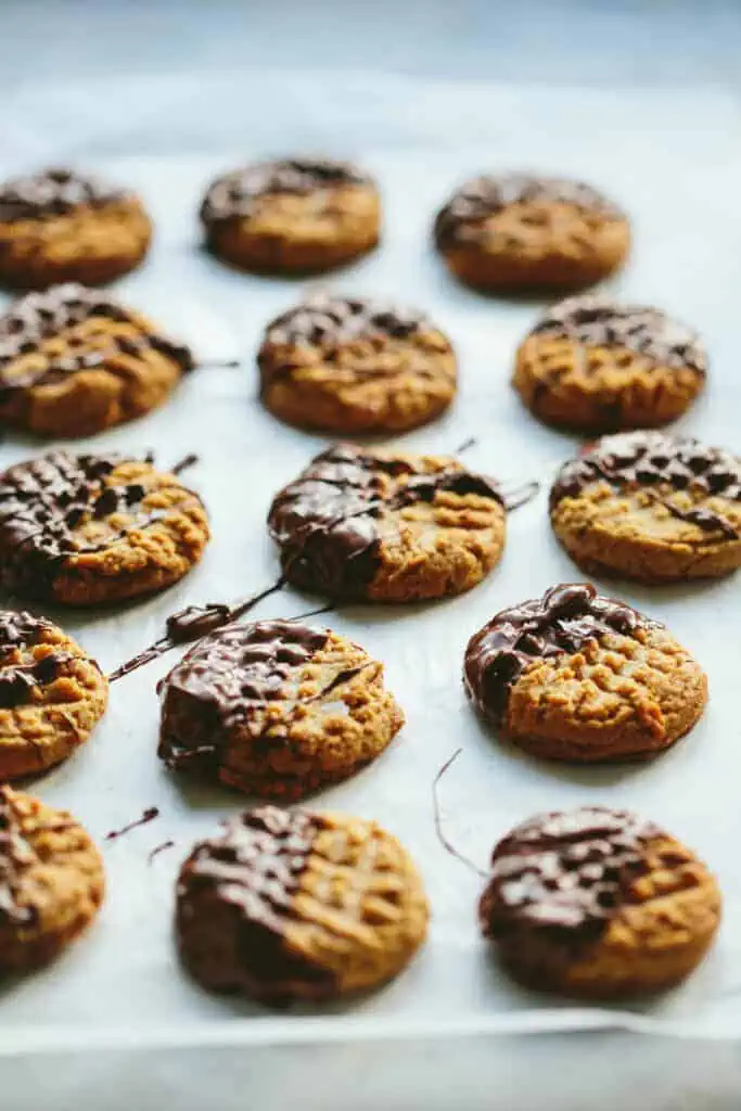 chocolate dipped peanut butter cookies on a sheet pan
