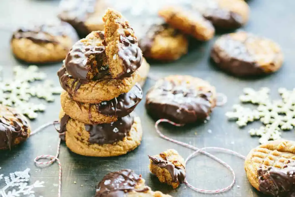 Stack chocolate-dipped peanut butter cookies on a wood table.