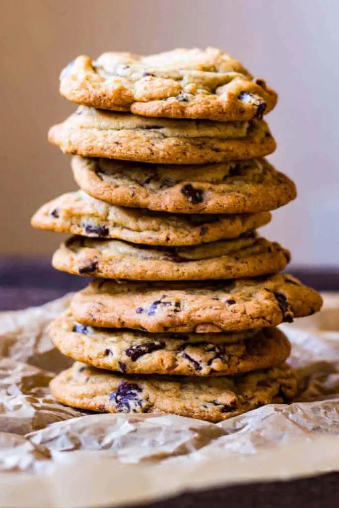 Close up side view vertical stack of chewy chocolate chunk cookies.