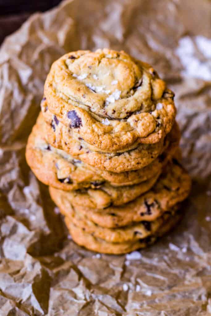 Close up of a vertical stack of chocolate chip cookies topped with flakey salt.