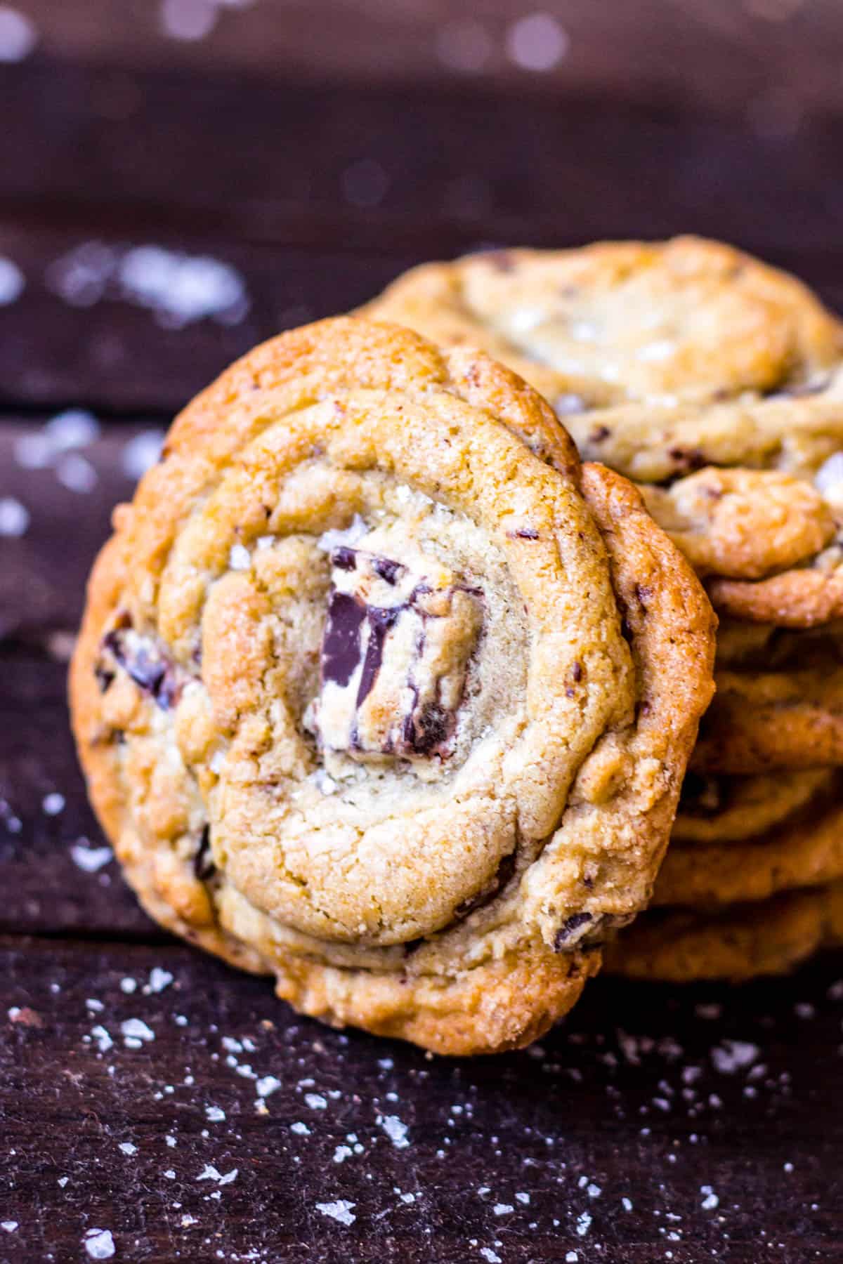 Front view of a chocolate chunk cookie leaning against a stack of more cookies.