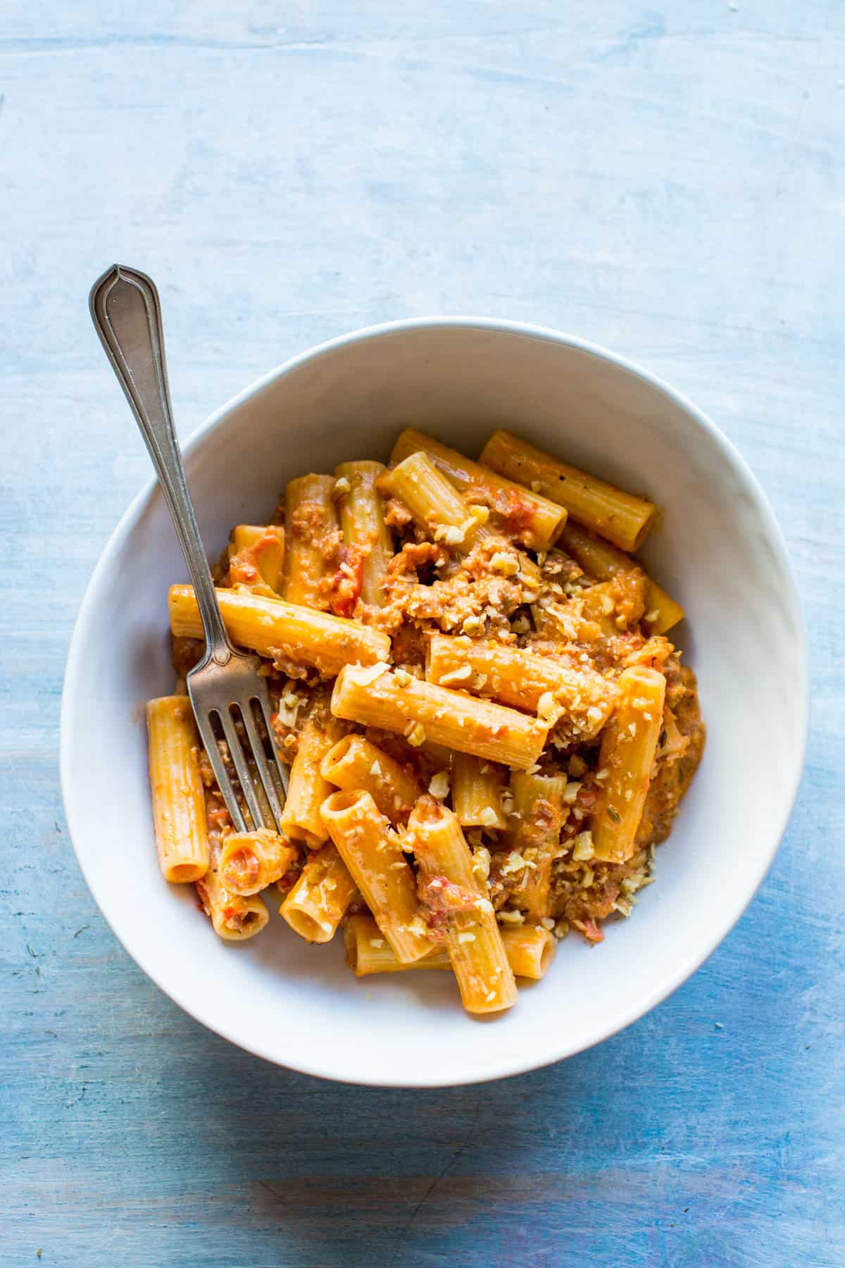 overhead shot of a white bowl with rigatoni and a fork