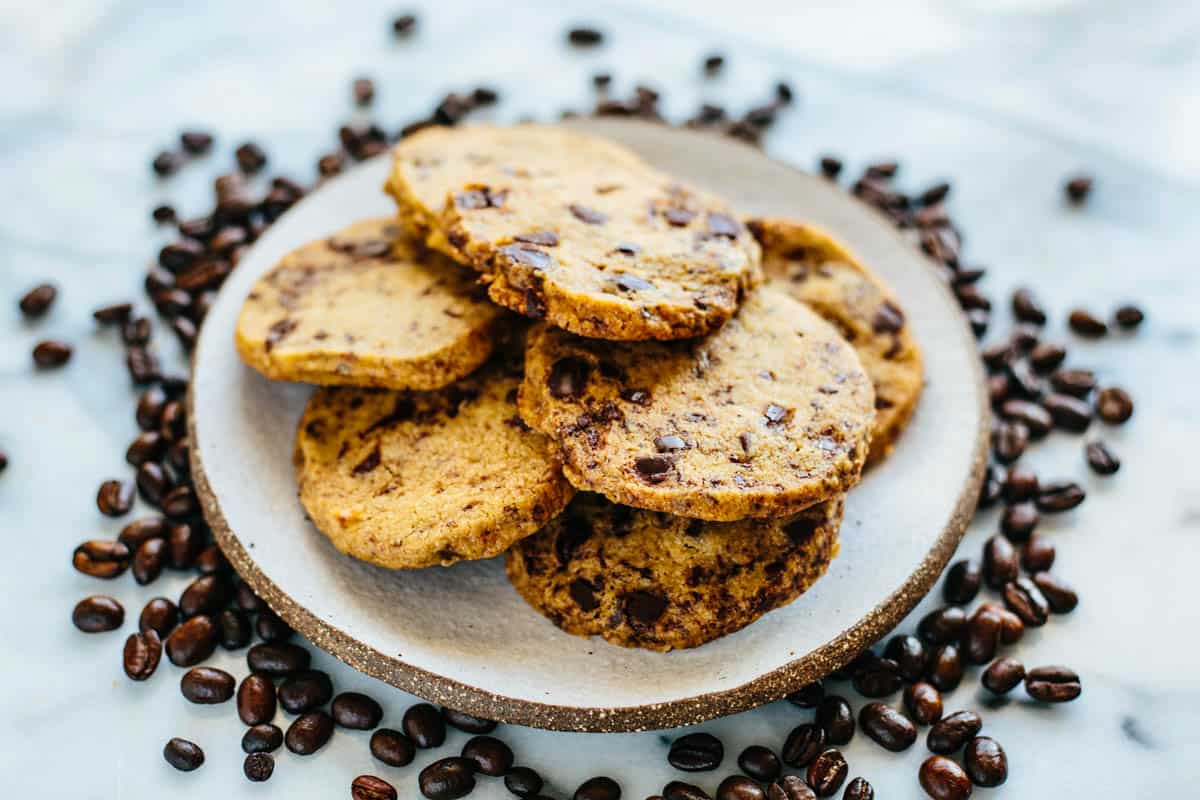 side view of a plate of cookies with coffee beans scattered around
