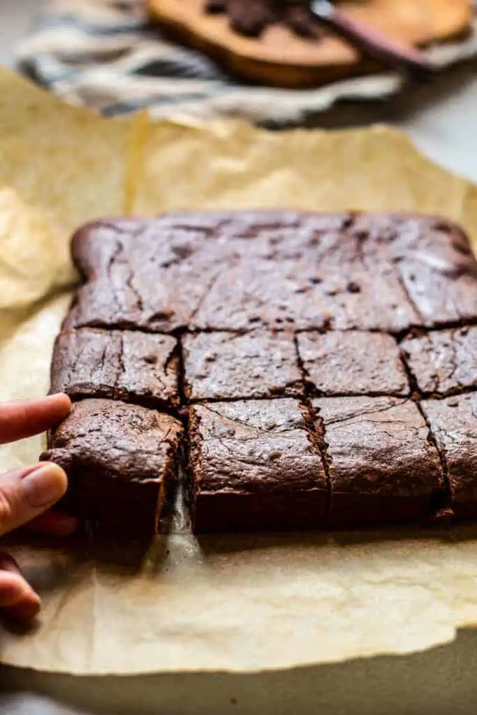 a hand pulling a brownie from a freshly cut batch