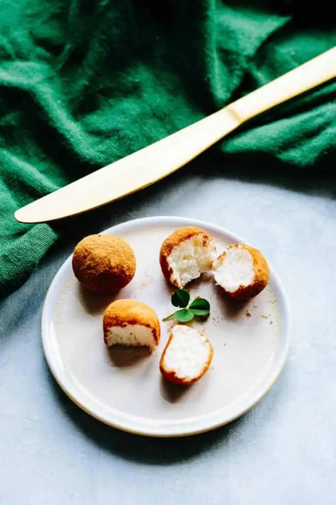 a small plate with a few Irish Potatoes cut in half with a gold knife and green napkin