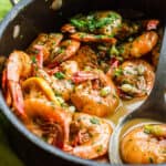 close up of a pan with saucy bbq shrimp with a serving spoon
