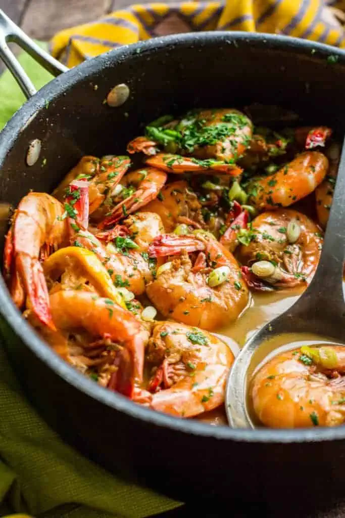 close up of a pan with saucy bbq shrimp with a serving spoon