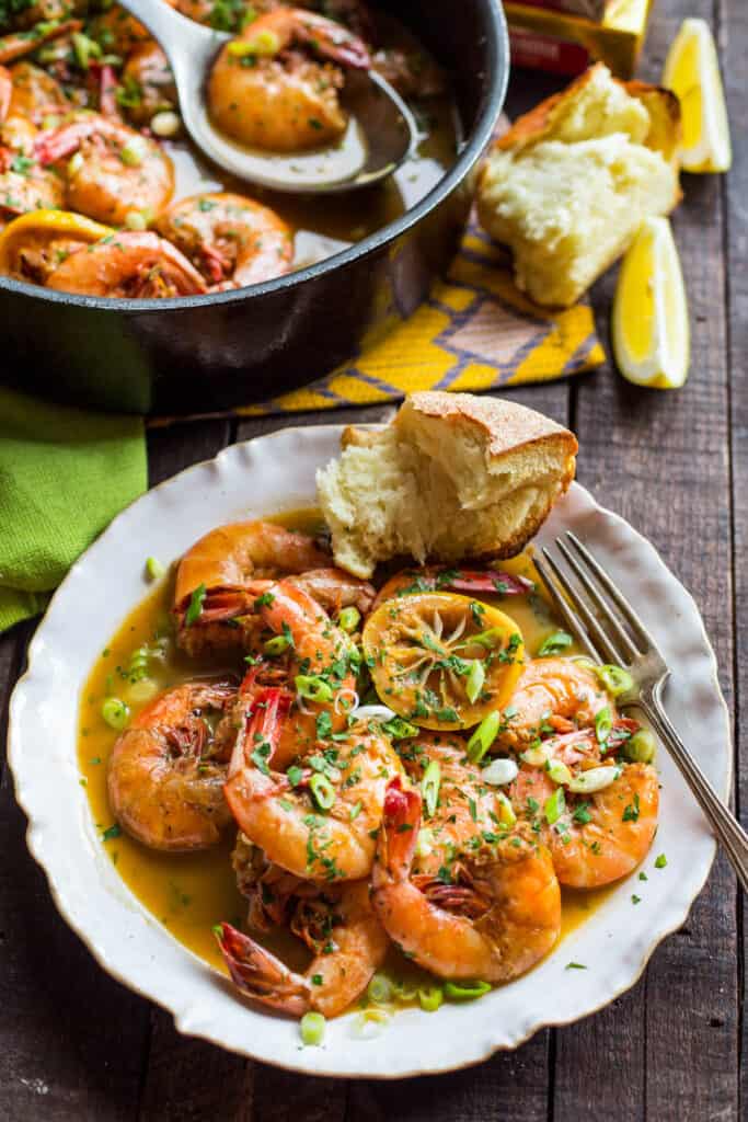a white plate with shrimp, lemon and bread