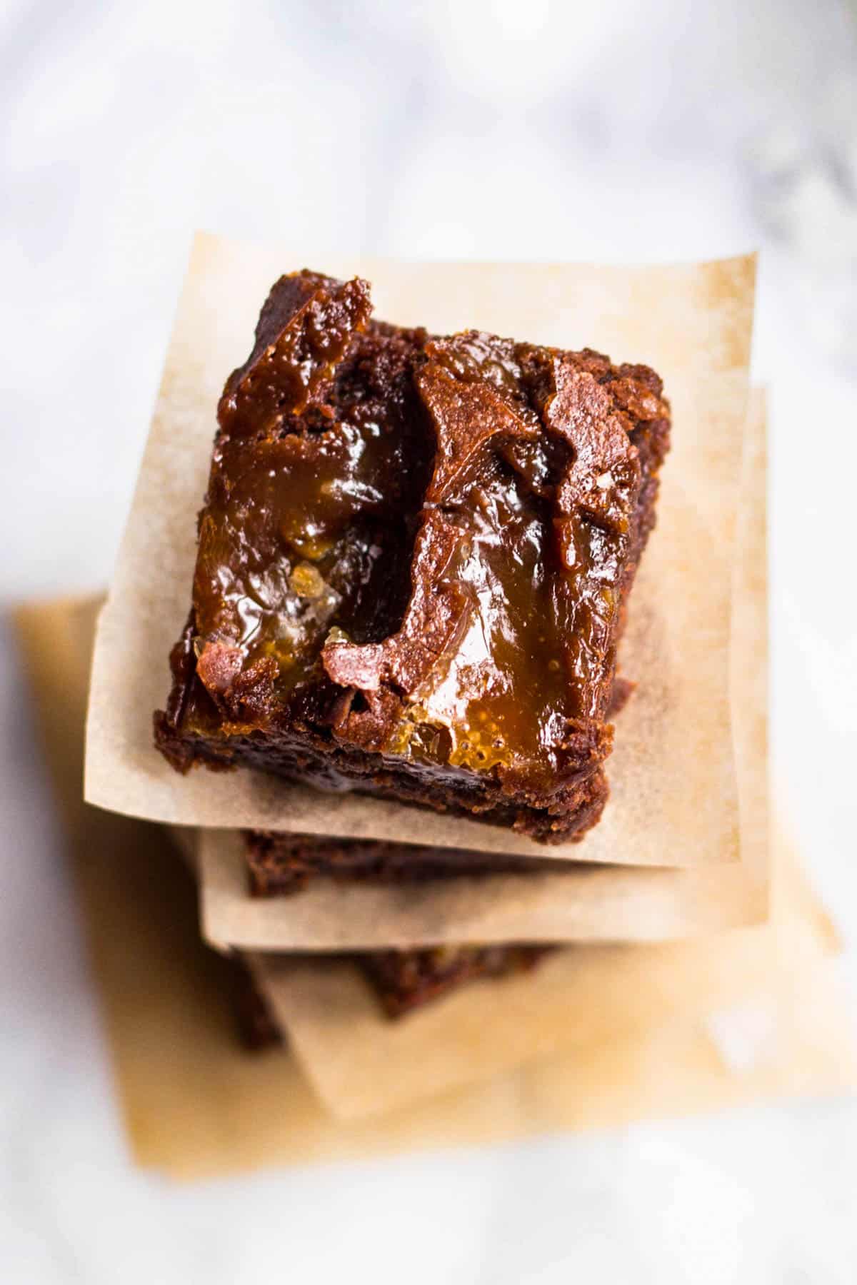 overhead view of a stack of brownies with brown parchment paper in between