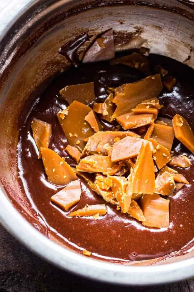 a bowl of brownie batter with pieces of caramel on top