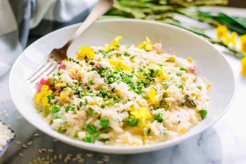 side view of a bowl of spring vegetable risotto with a fork