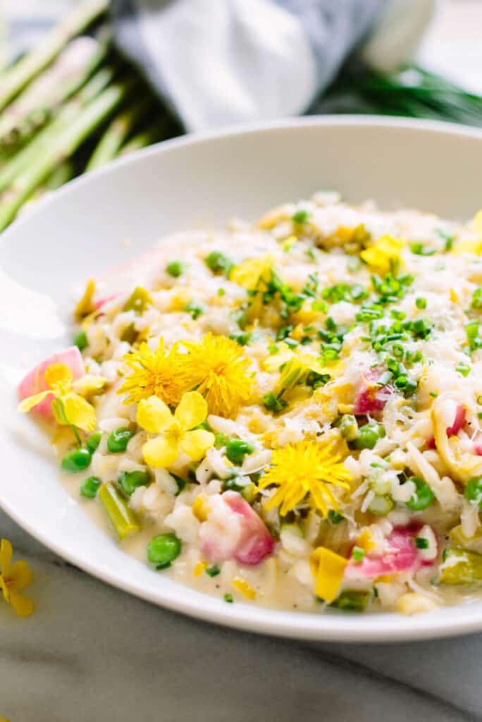 close up of spring vegetable risotto with flower garnish