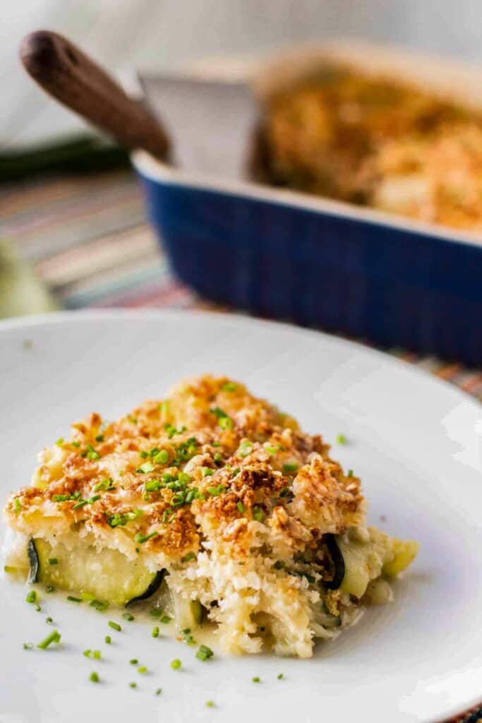 A square serving of zucchini gratin on a white plate.