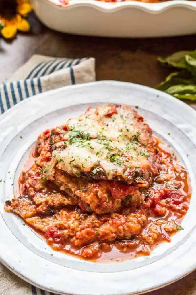 Serving of eggplant Parmesan on a white dinner plate.