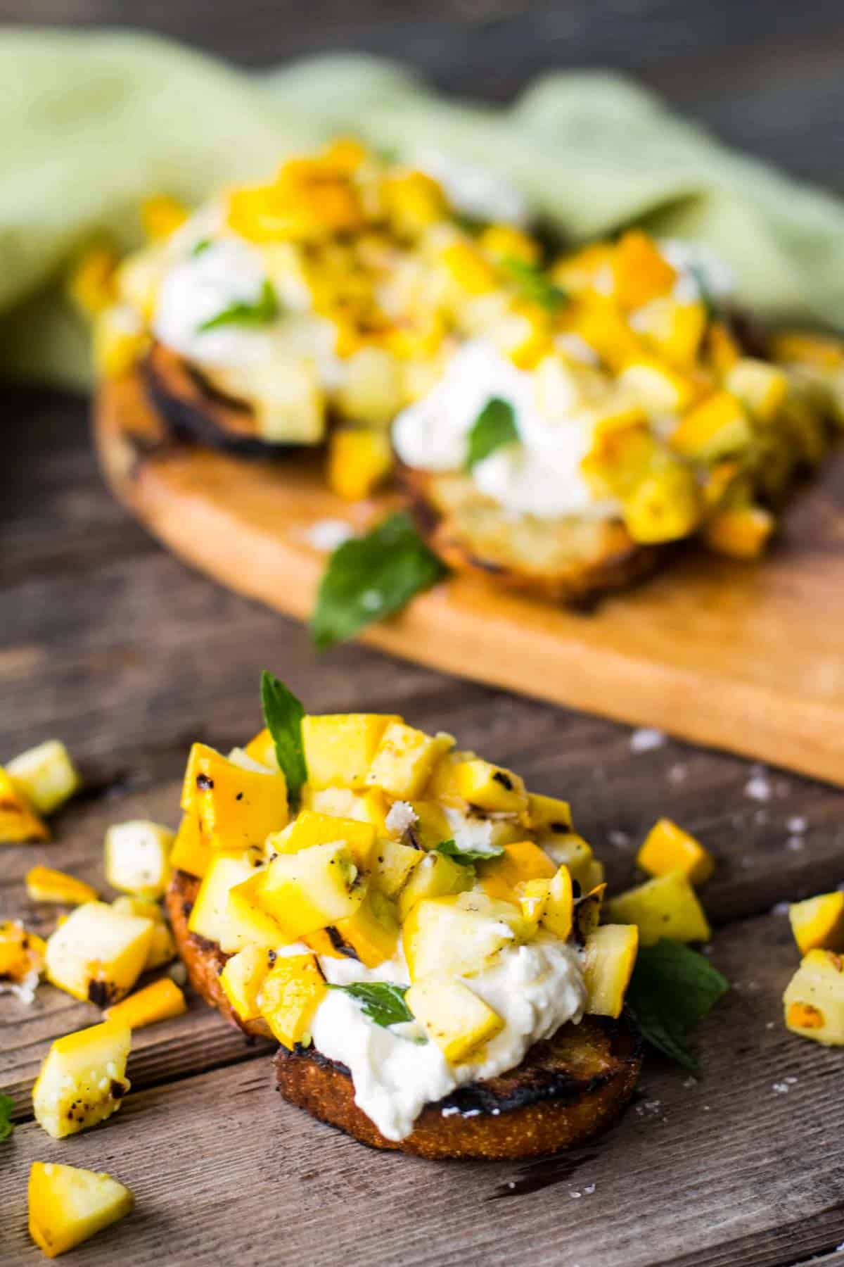 piece of zucchini bruschetta in front of a platter of them