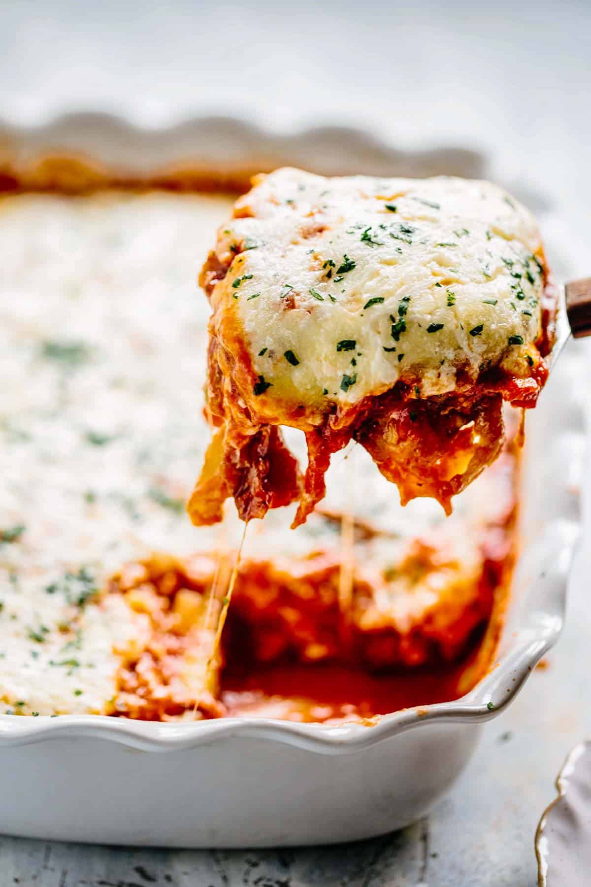 a spatula scooping out a square of eggplant parmigiana