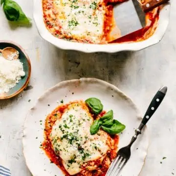 Vertical shot of eggplant parmesan on a plate next to a baking dish.