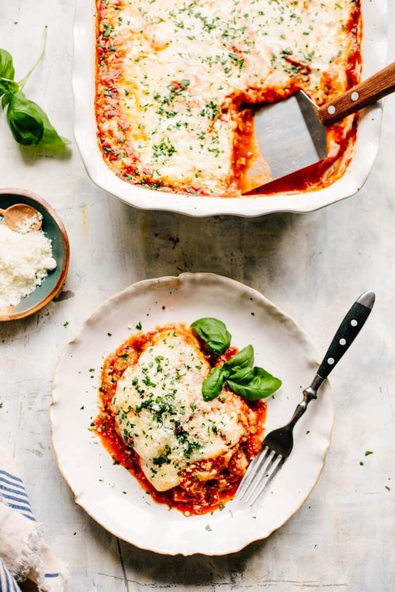 Vertical shot of eggplant parmesan on a plate next to a baking dish.