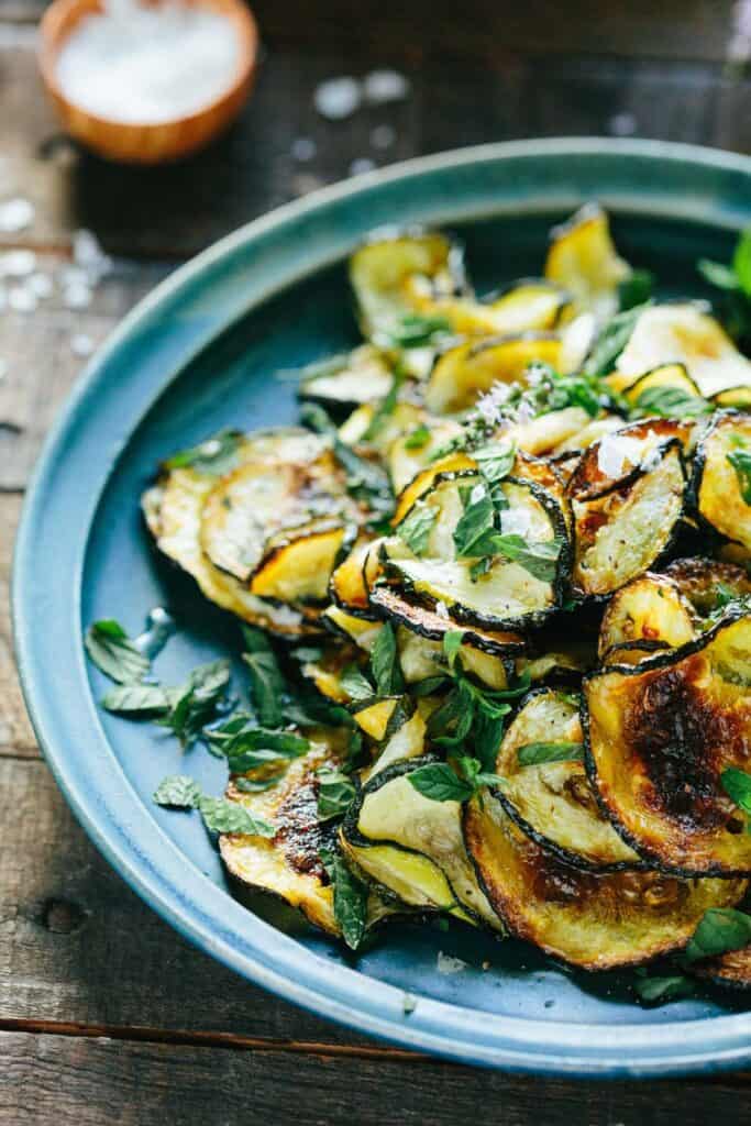 Serving bowl of thinly sliced and roasted summer squash.