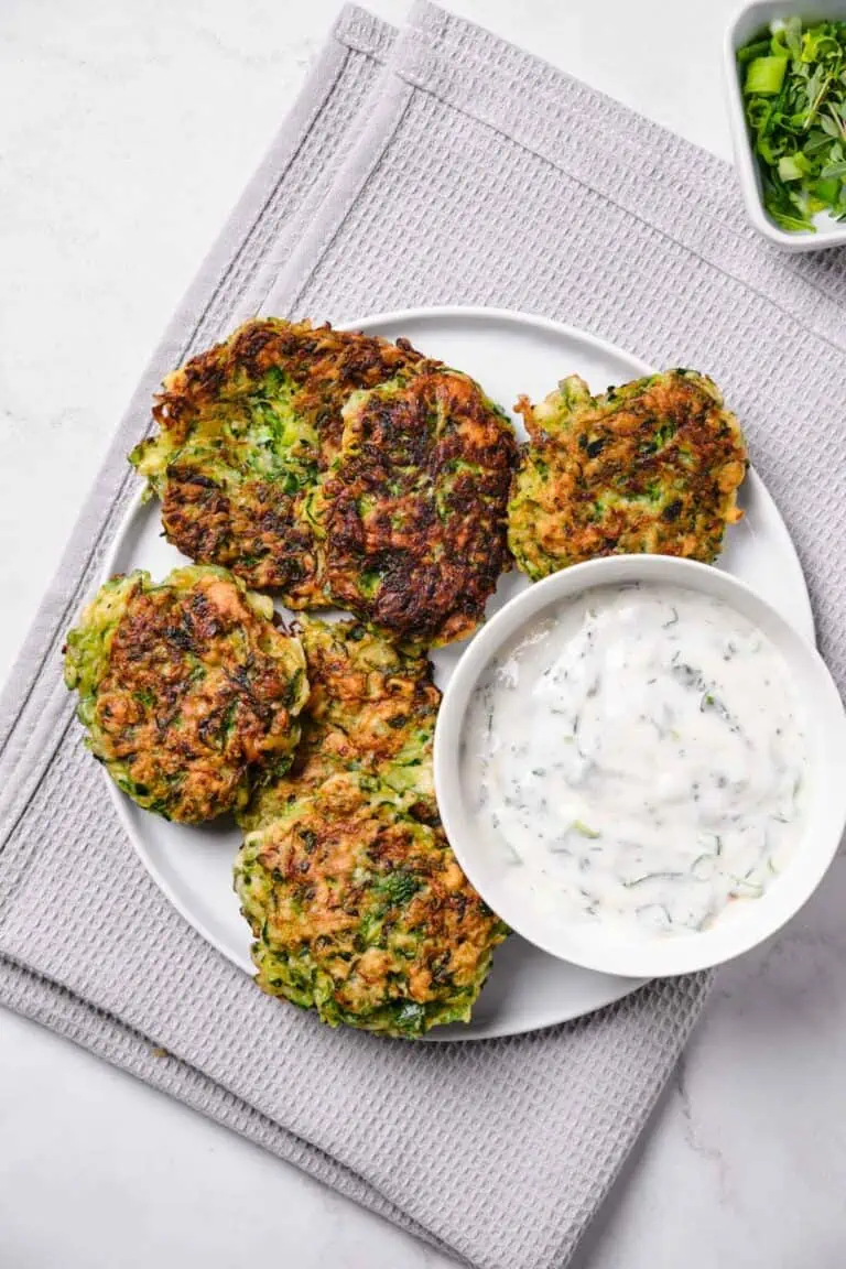 Top view of a plate of zucchini fritters with lemon herb yogurt dip.
