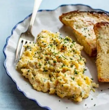 close up of scrambled eggs on a plate with a fork