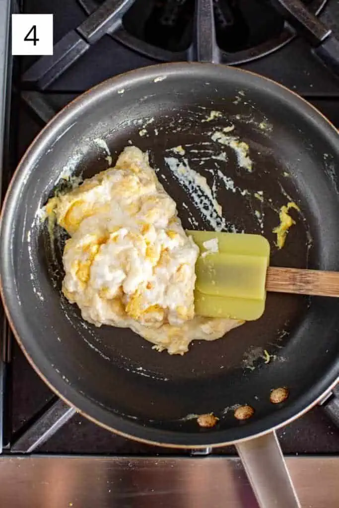 overhead shot of a spatula folding ricotta into scrambled eggs