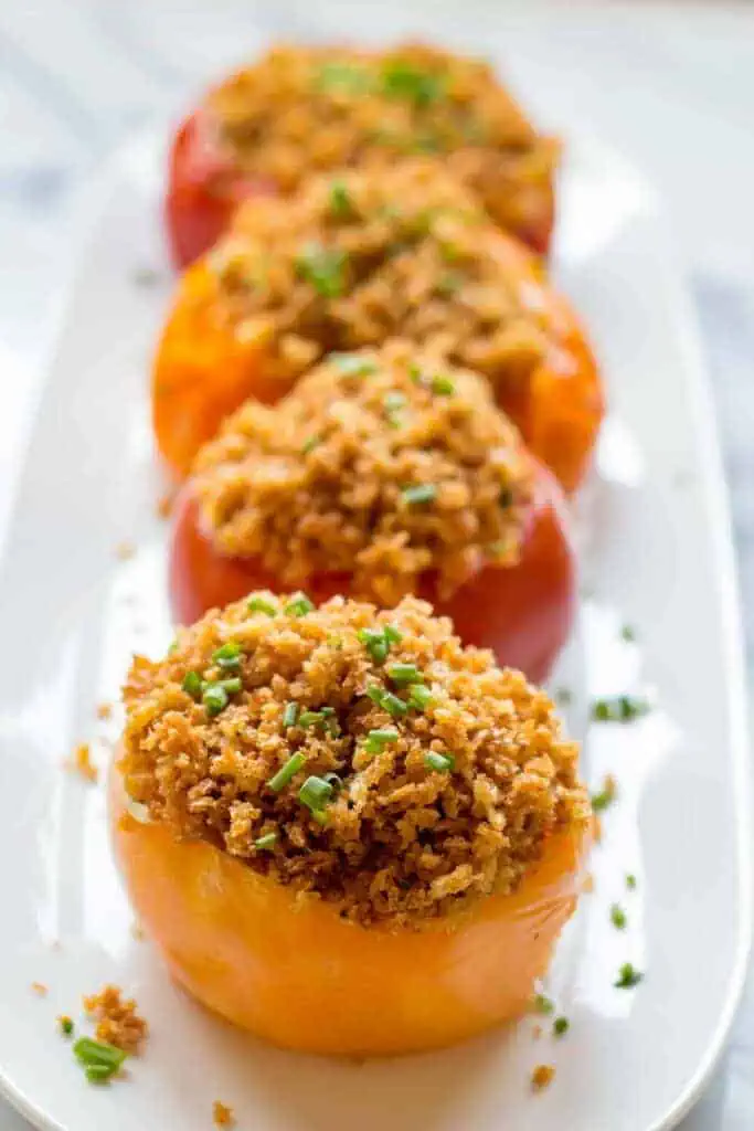Side view of baked tomatoes with breadcrumbs on top.