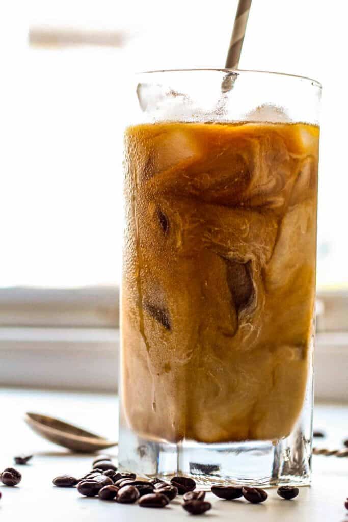 Side view of a glass of iced cold brew coffee with condensation on the outside.