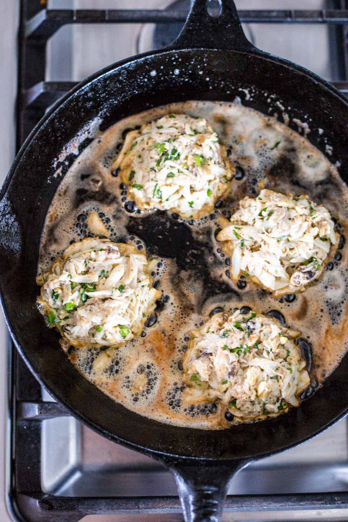 crab cakes being pan fried in butter