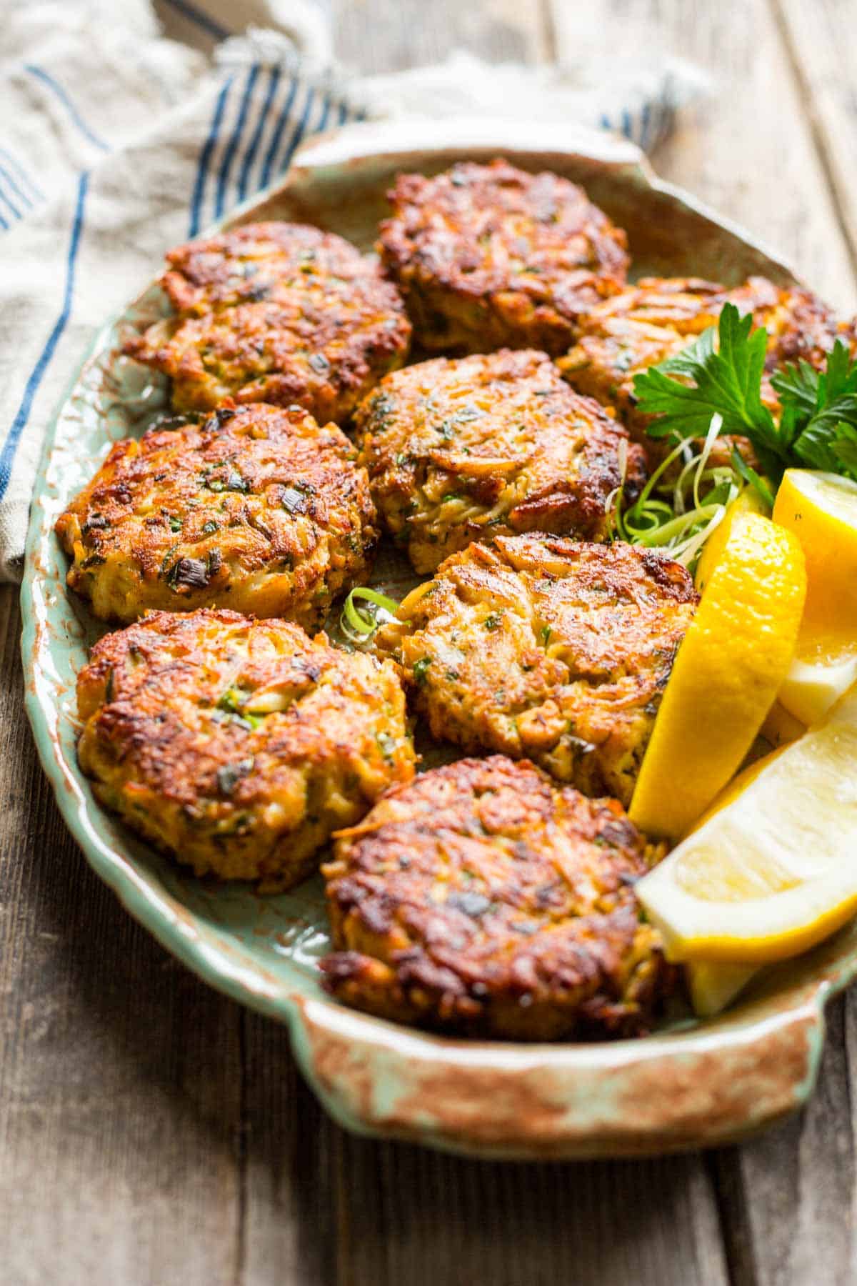 side view of a plate of crab cakes with lemons