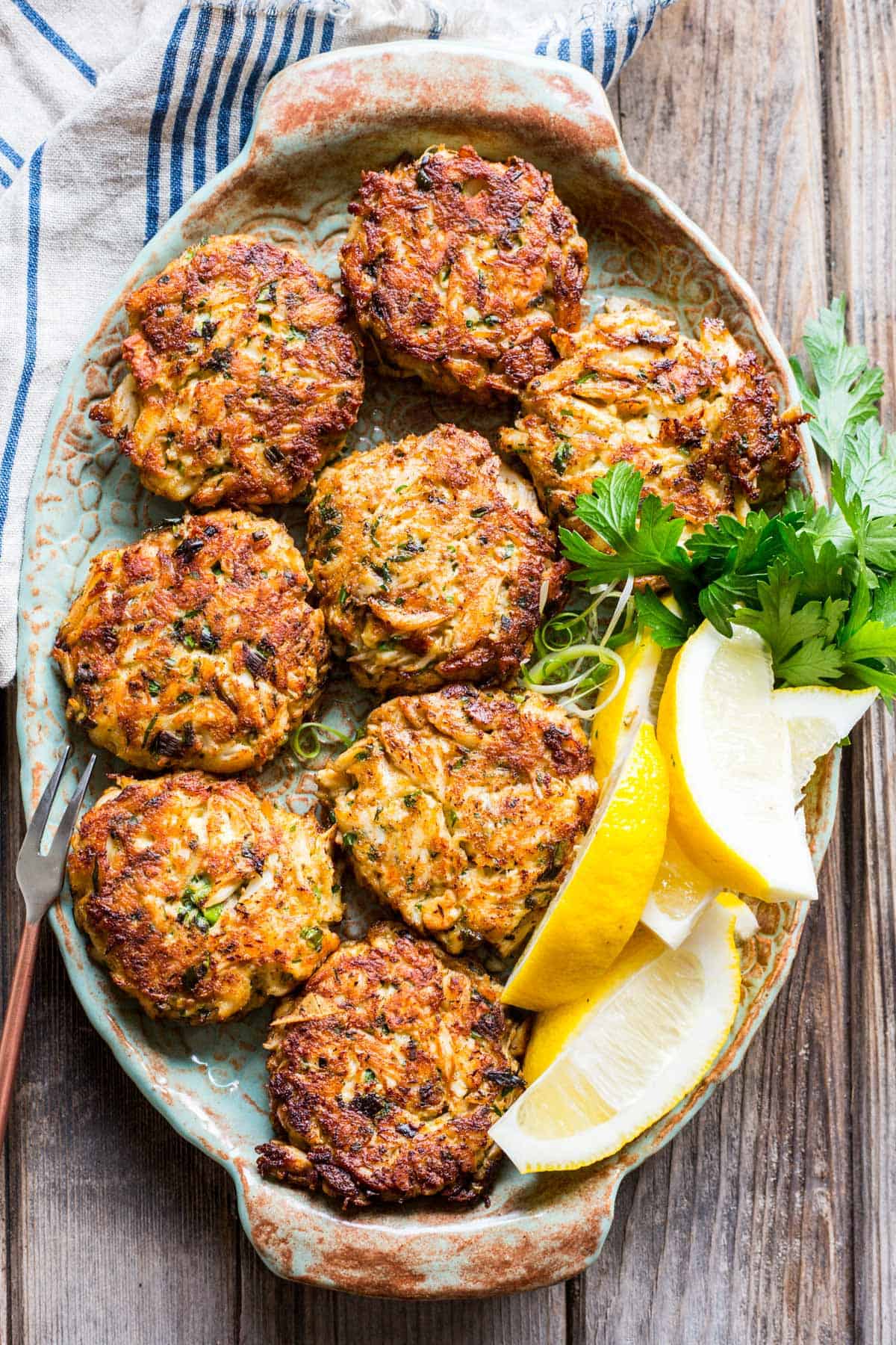 overhead shot of a platter with crab cakes and lemon wedges on top