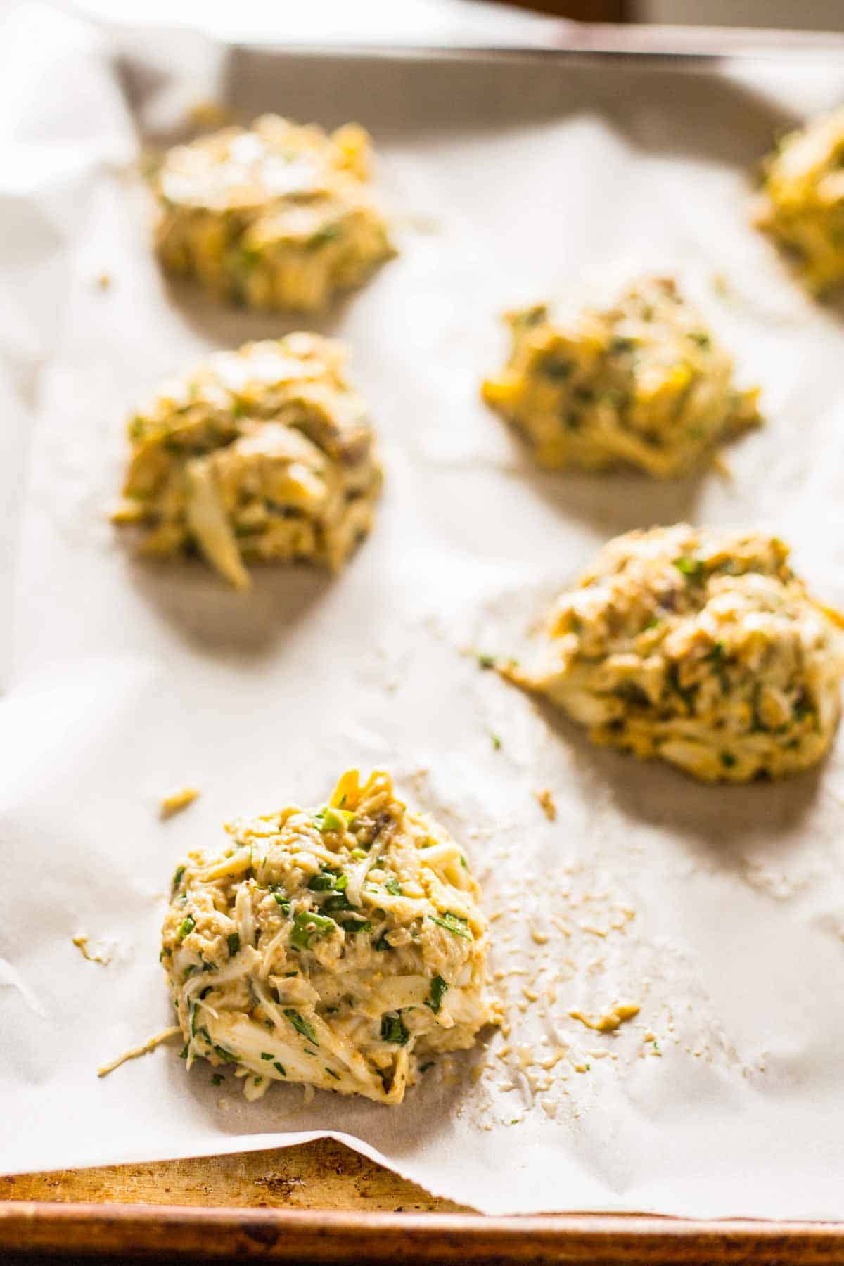 raw crab cakes on a parchment lined baking sheet