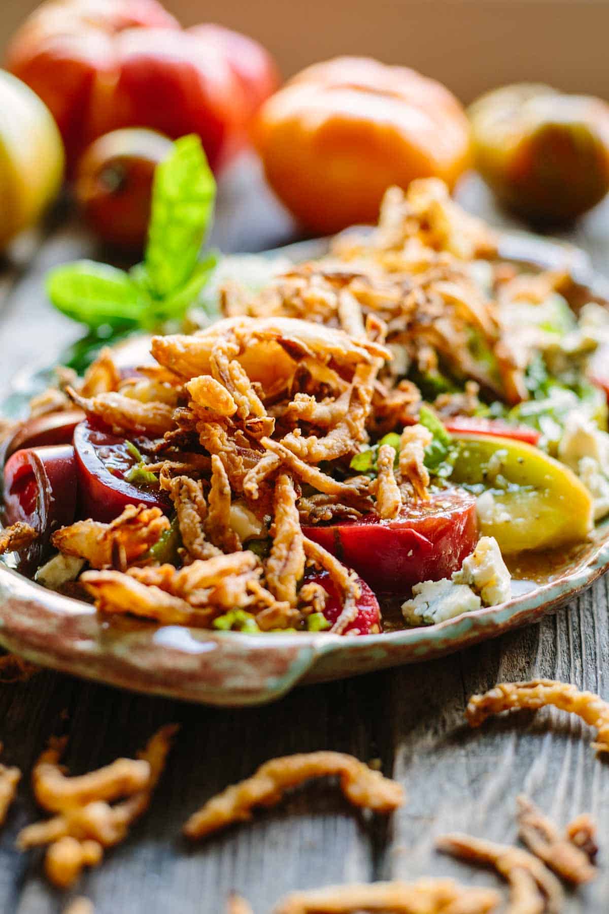 Heirloom tomato salad on a platter with fried onions.