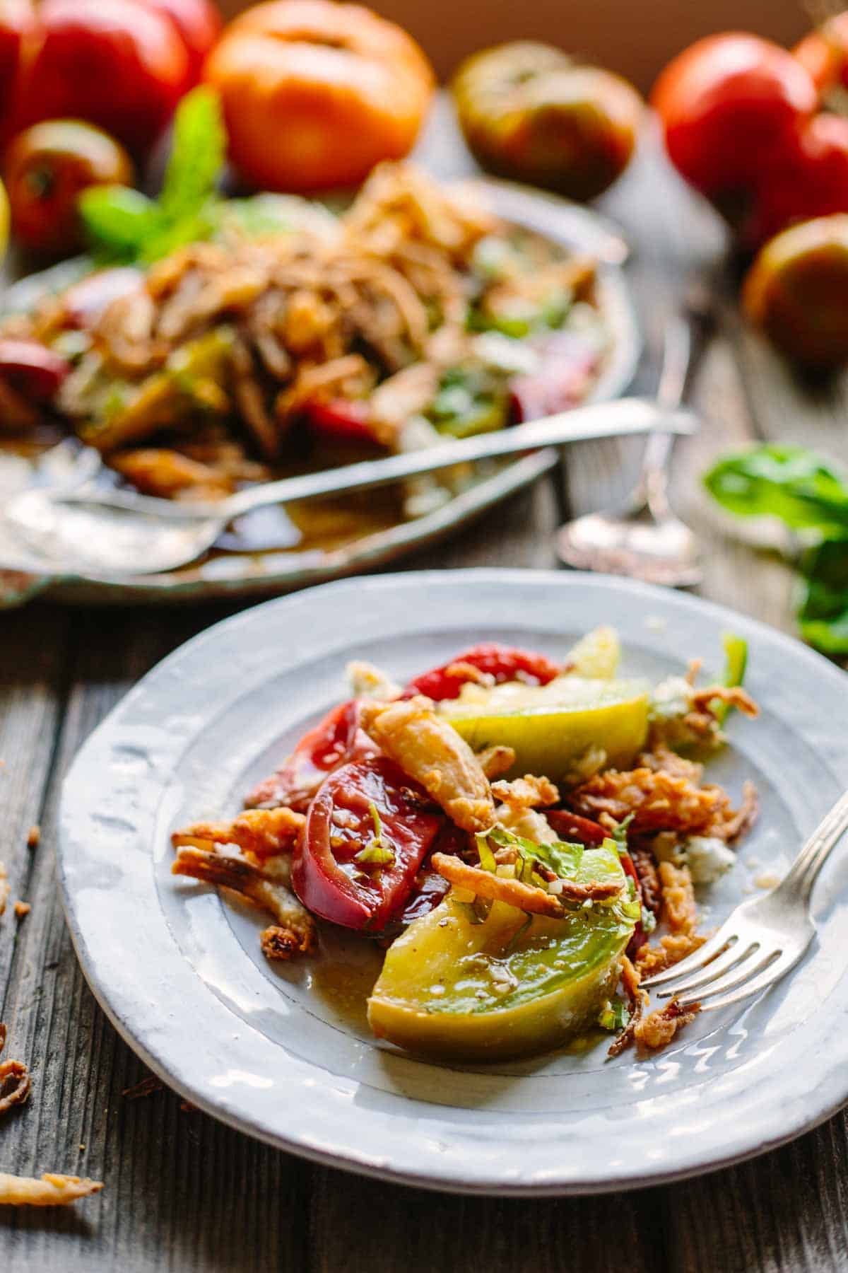 A gray ceramic plate with green and red tomatoes and a fork.