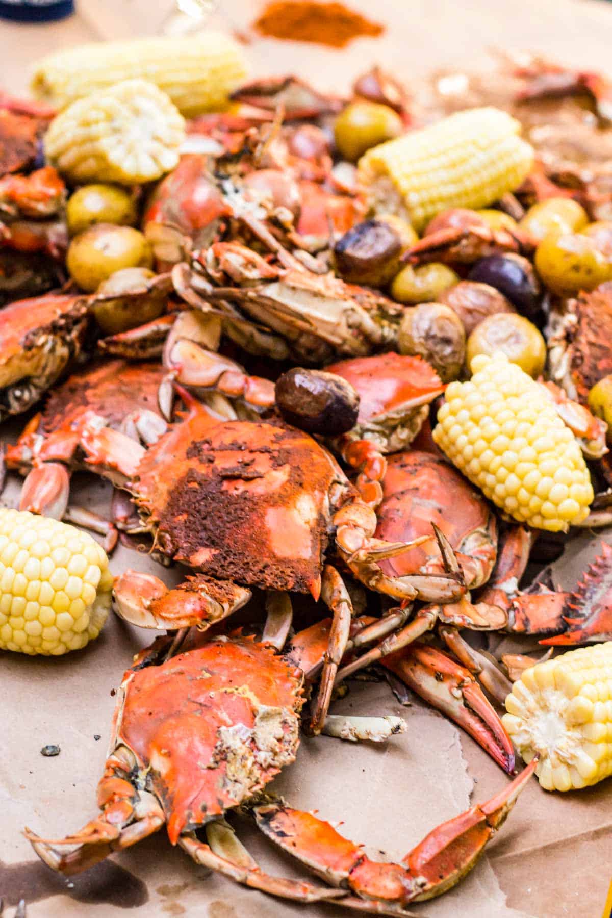 Close up of a pile of steamed crabs and corn on the cob.