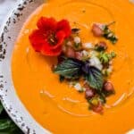 A bowl of gazpacho garnished with an edible flower.