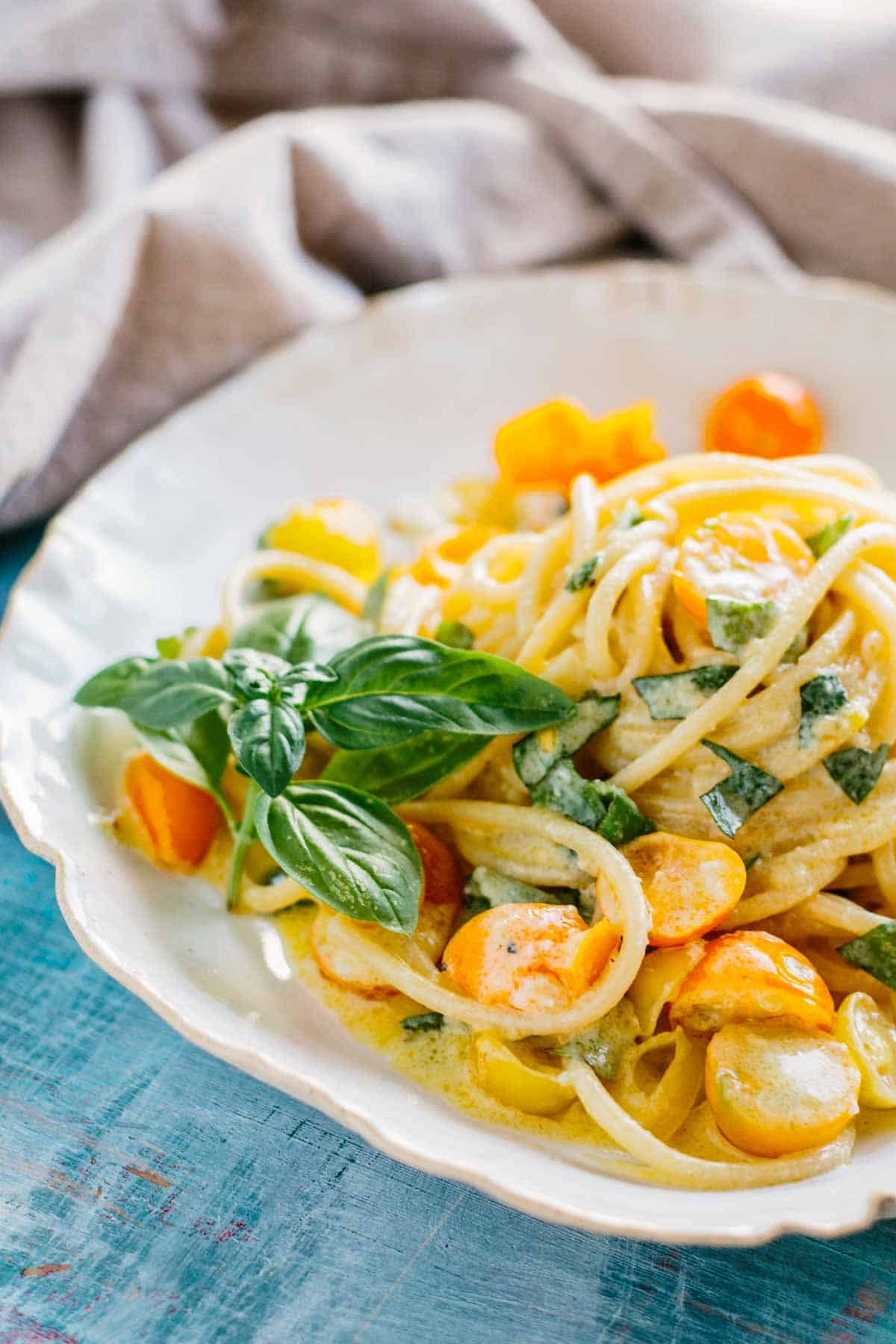 Close up of a bowl of pasta with yellow tomatoes.