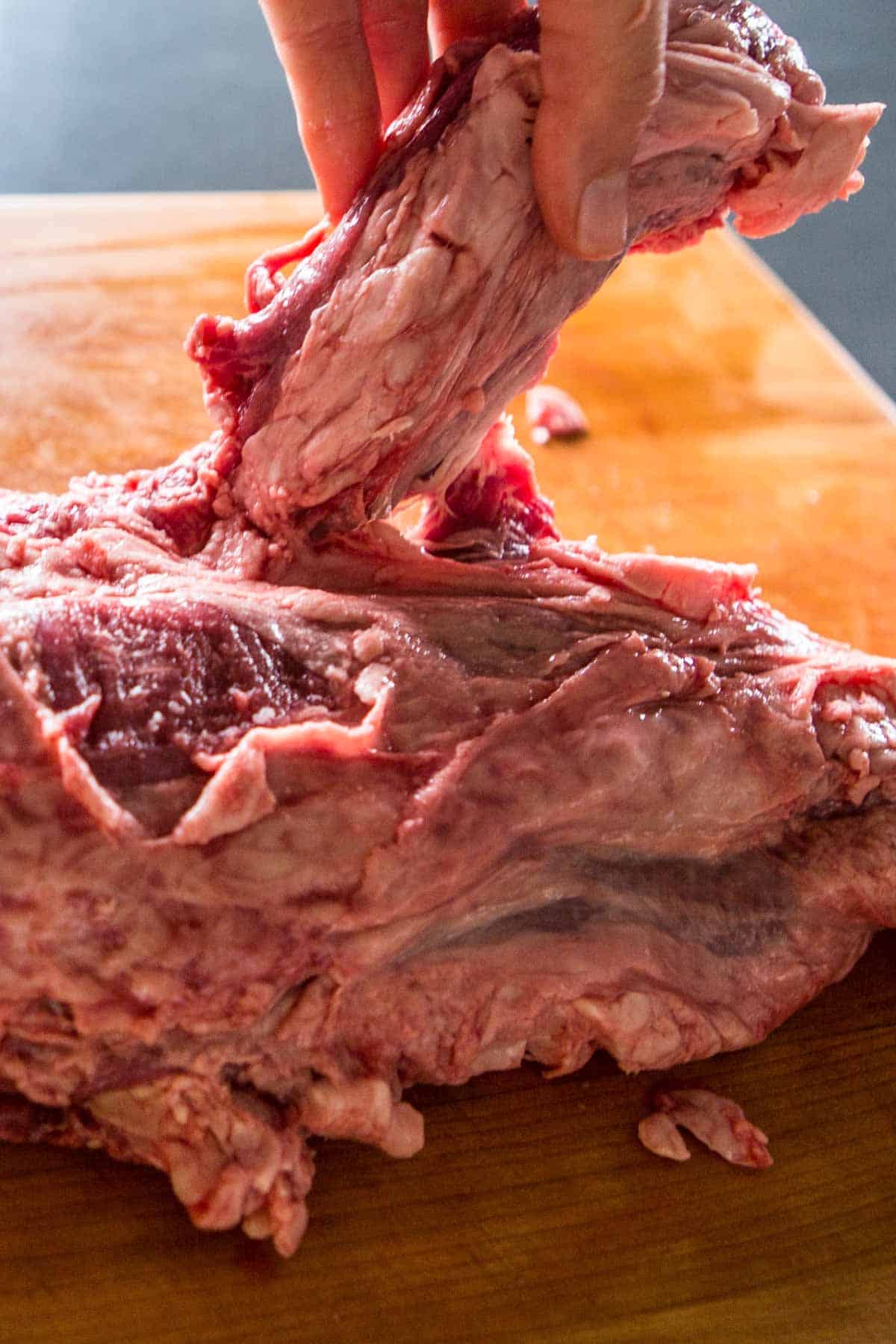 Close up of the chain being removed from a raw beef tenderloin.