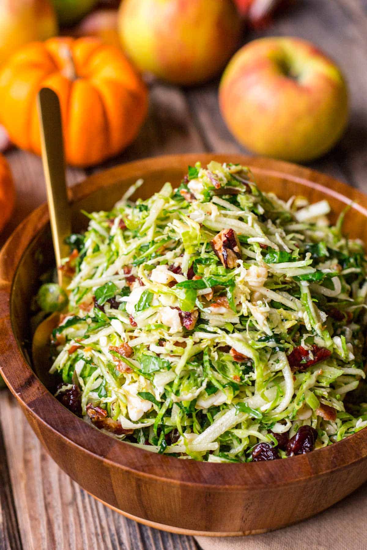 Side view of a shaved Brussels sprout salad in a wooden bowl.