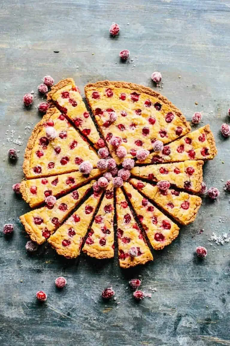 Top view of a cranberry tart sliced and topped with sugared berries. 