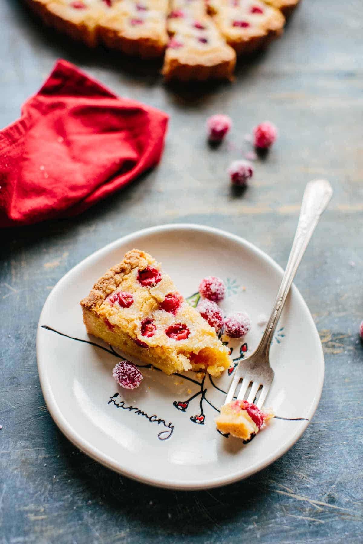 A slice of cranberry tart on a white plate with a fork.