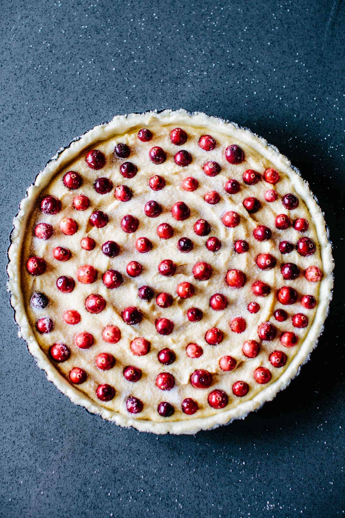 Overhead shot of an unbaked Frangipane Tart with cranberries dotted throughout.
