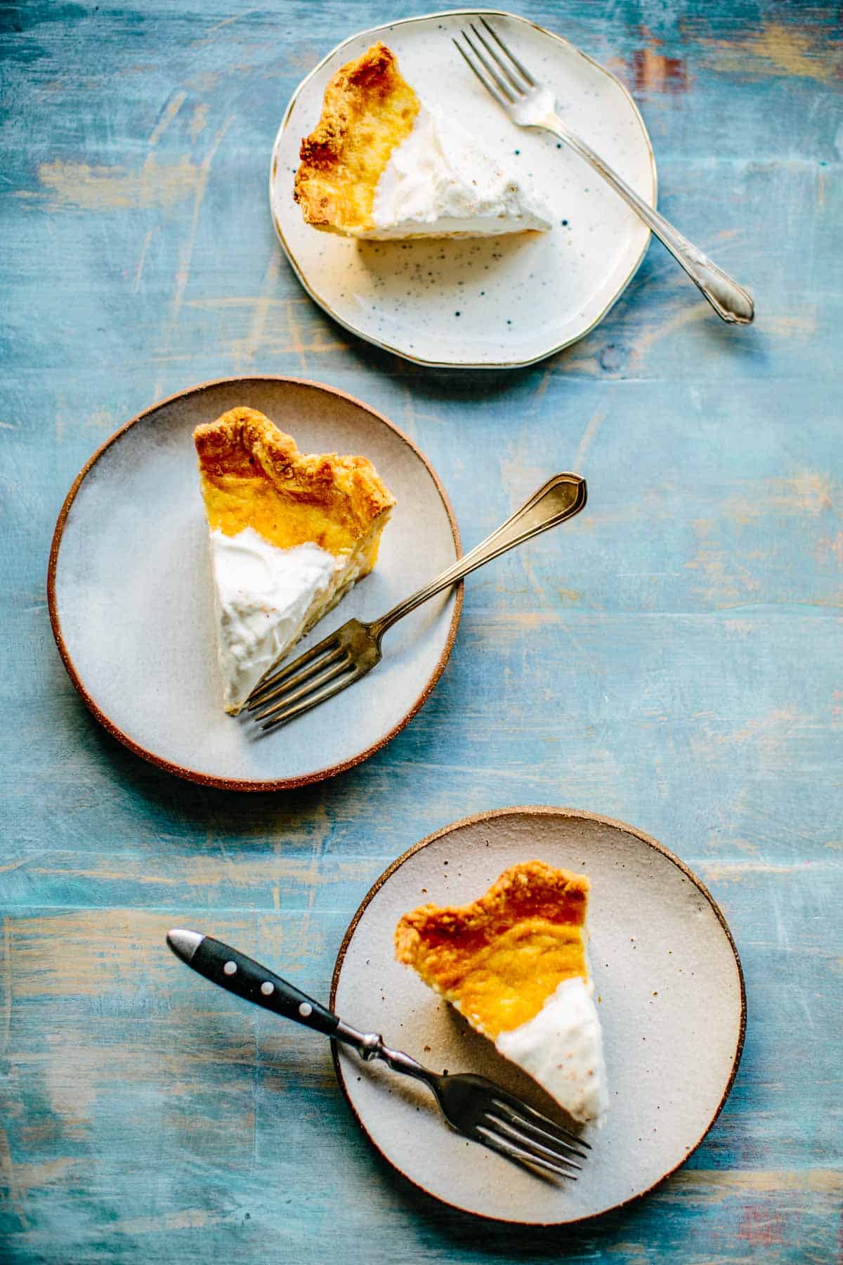 Overhead view of 3 white plates with slices of pie and a fork on each.