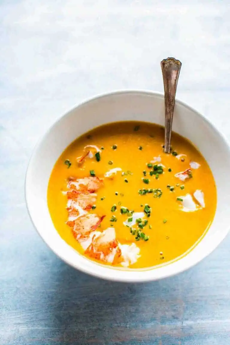 A bright, creamy lobster bisque in a white bowl.