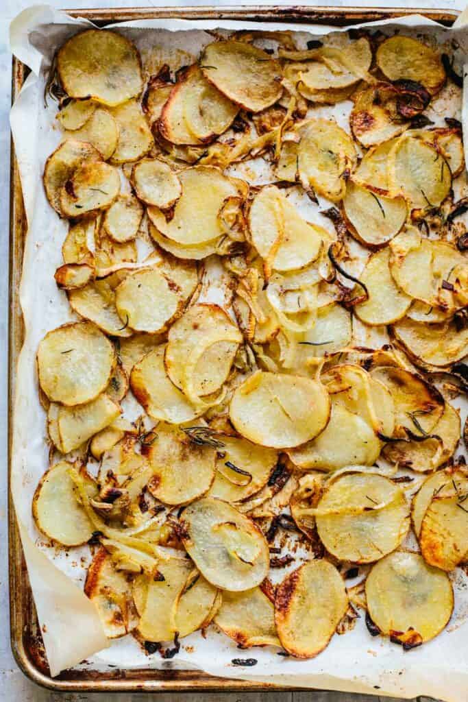 Overhead shot of cooked potatoes and onions on a sheet pan.