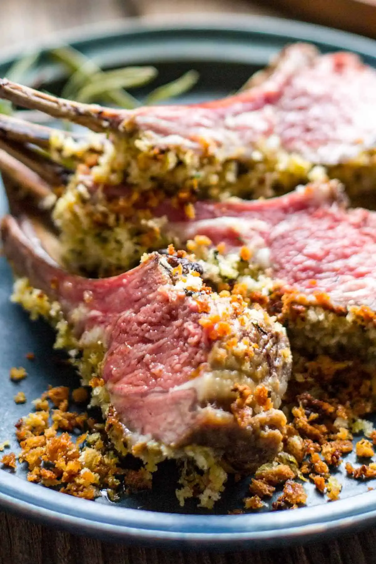 Close up of three lamb chops set on their side on a dinner plate.