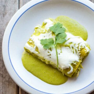 Top view of two Enchiladas Suizas on a gray plate garnished with cilantro.