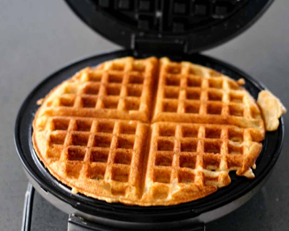A cooked waffle inside of an opened waffle maker.